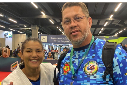 A campeã olímpica Sarah Menezes posa sorridente ao lado de Adalberto Corrêa, da CBSA, na COB Expo