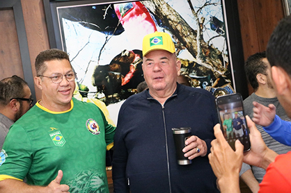Adalberto Corrêa e Vasily Shestakov sorriem enquanto são fotografados com um celular