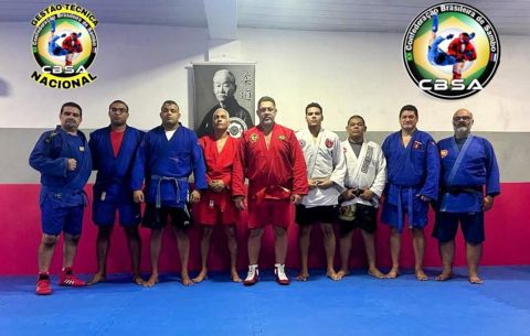 Professores do curso de SAMBO em Pernambuco, de quimonos azuis, vermelhos e brancos, enfileirados no tatame
